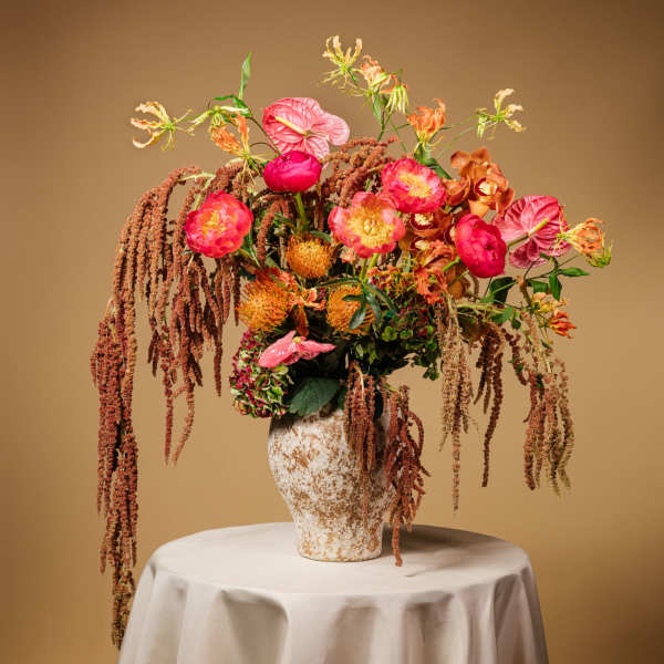 Tall floral arrangement in a textured vase with pink and orange blooms