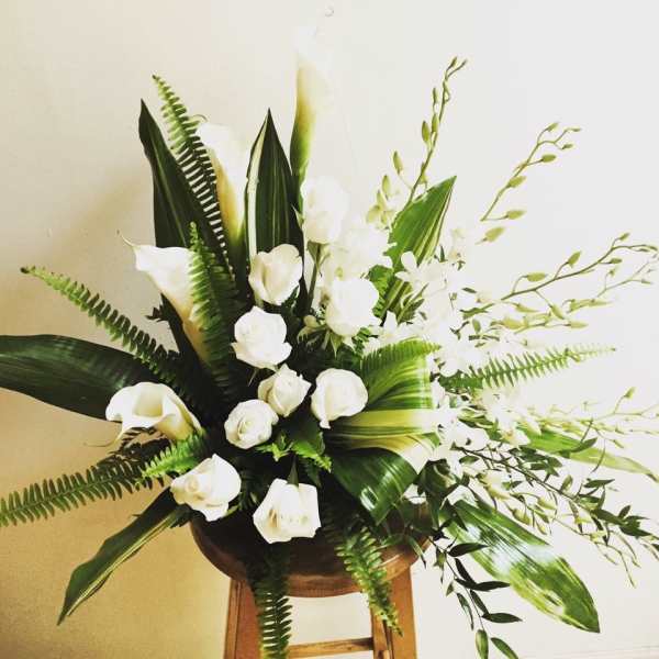 White calla lilies and roses in a wooden stand arrangement