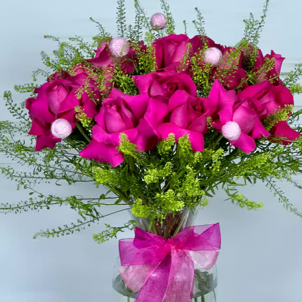 Bouquet of hot pink roses in a glass vase with a pink ribbon