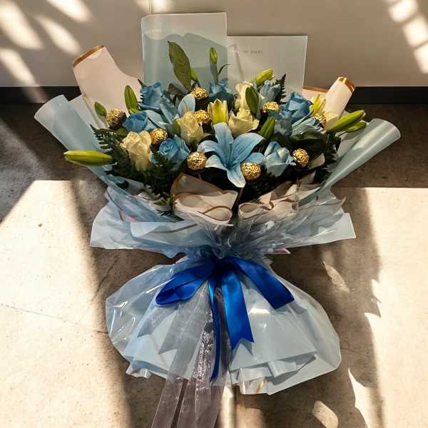 Bouquet of blue and white flowers wrapped in pale blue paper with a blue ribbon
