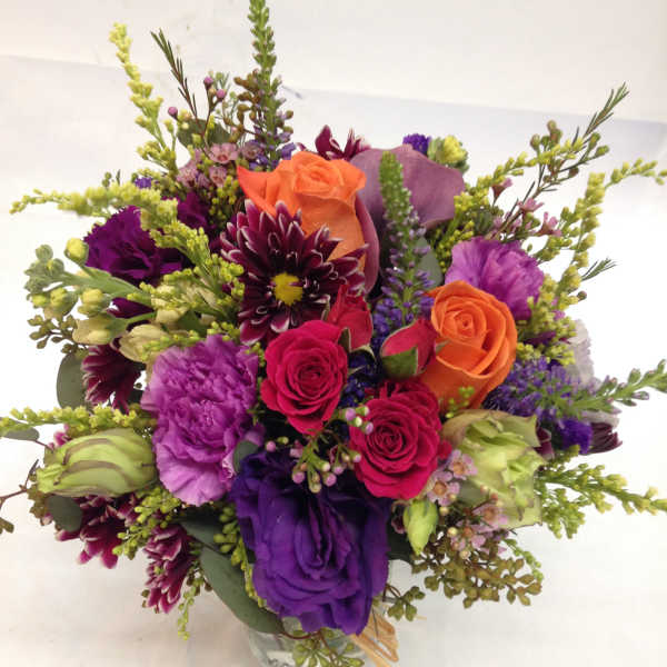 Mixed bouquet of purple, pink, and orange flowers in a glass vase