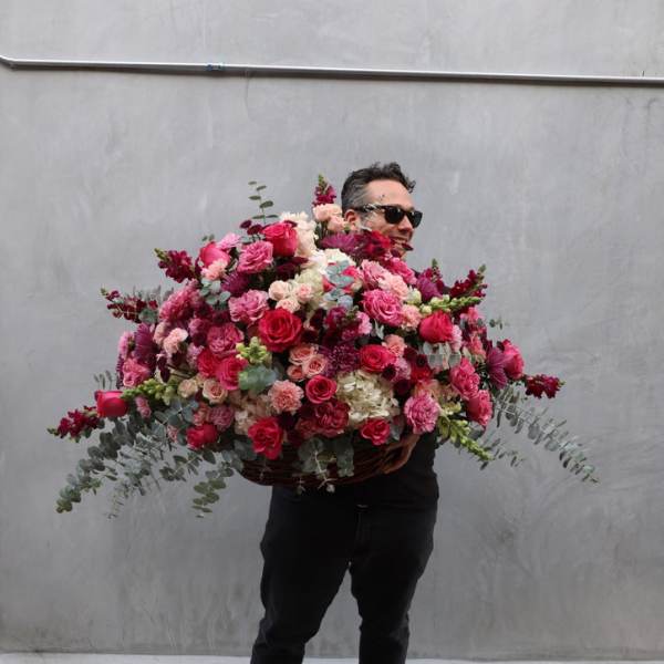 Man holding a huge mixed pink and red flower arrangement