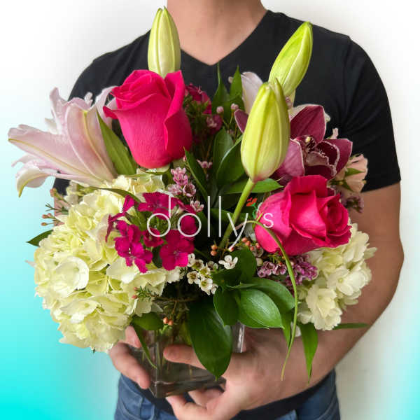 Bouquet of pink roses, lilies, and hydrangeas in a glass vase