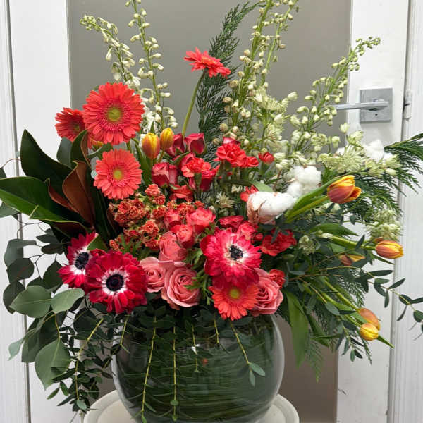Large mixed flower arrangement in a glass vase with pink and red blooms