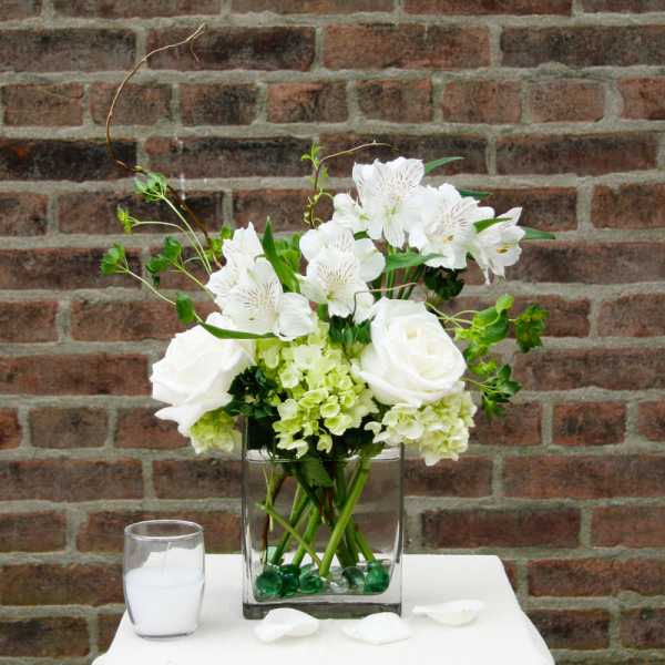 White roses and alstroemeria in a square glass vase with green hydrangea