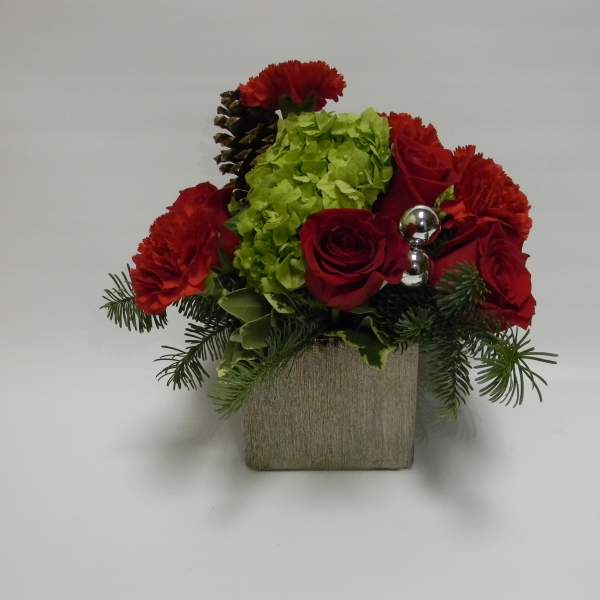 Red roses and carnations in a square vase with green hydrangea