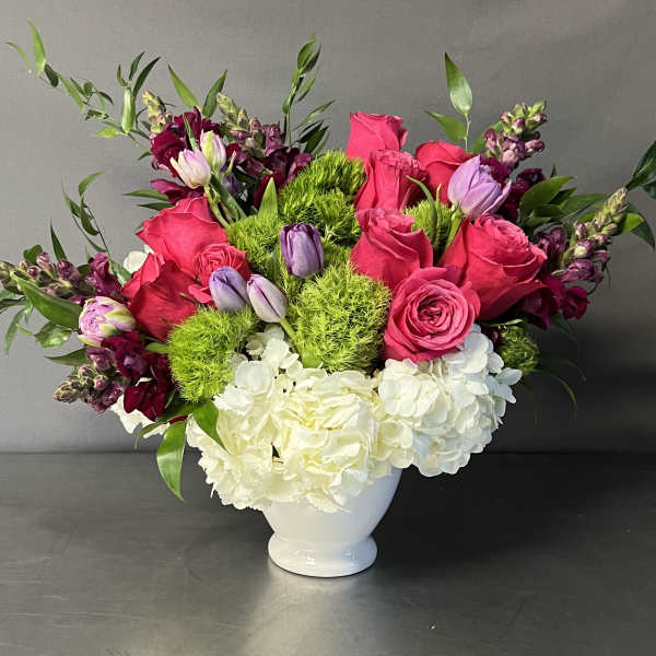 Pink roses and white hydrangeas in a white vase with green accents