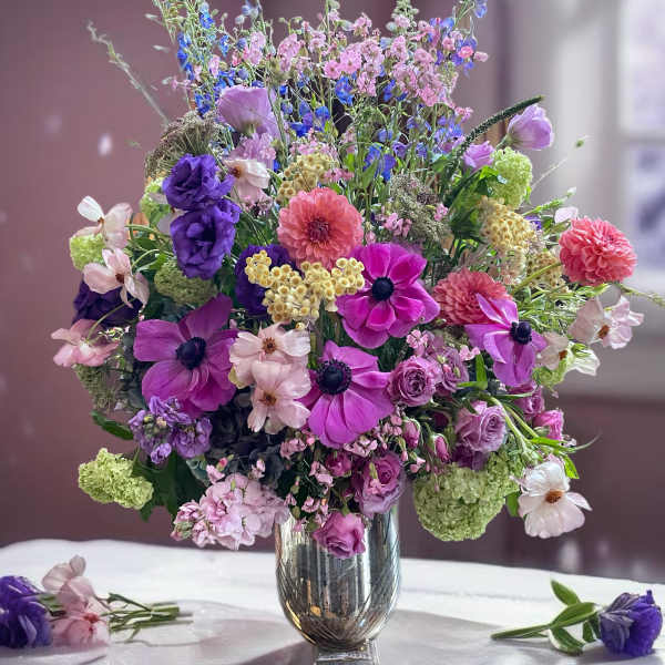 Mixed bouquet of purple, pink, and white flowers in a silver vase