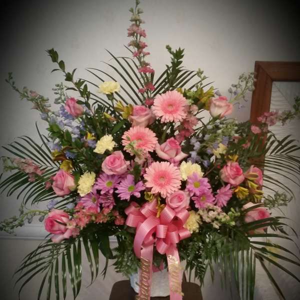 Large pink and purple floral standing arrangement with a ribbon bow