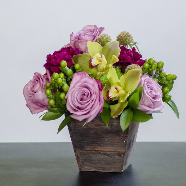 Pink roses and yellow orchids in a wooden container