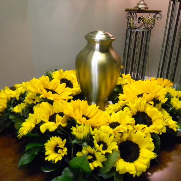 Sunflower wreath around a gold urn on a table
