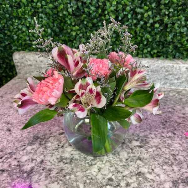 Pink and white flowers arranged in a clear glass bowl vase