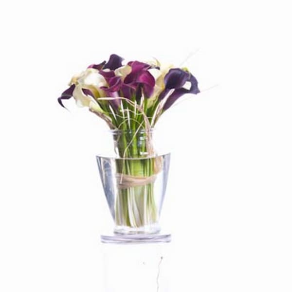 Bouquet of purple and white calla lilies in a clear glass vase