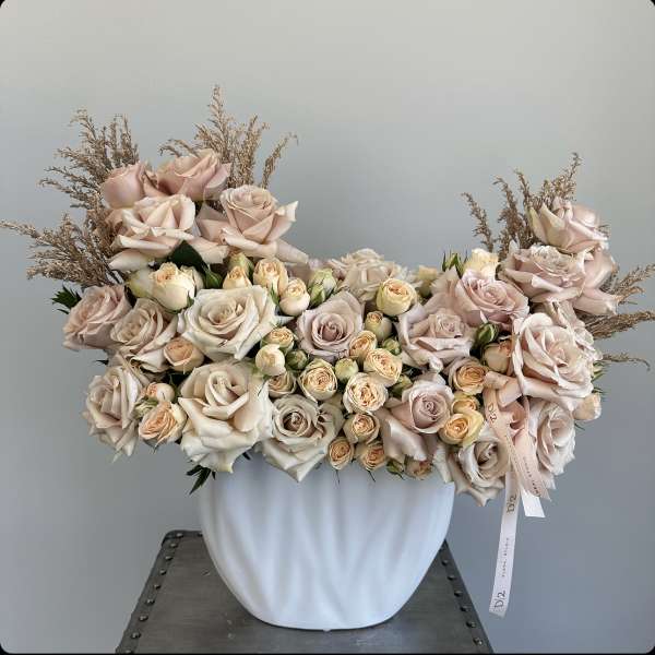 Large bouquet of pale pink and cream roses in a white vase
