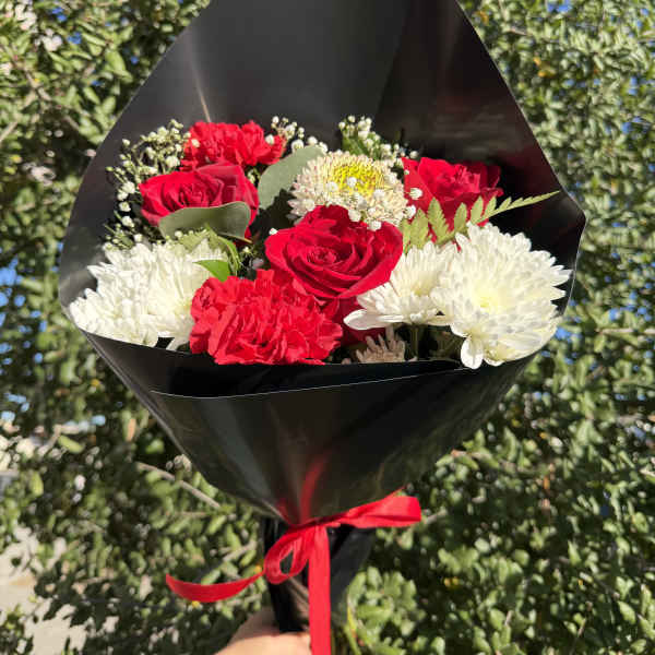 Bouquet of red roses and white chrysanthemums wrapped in black paper