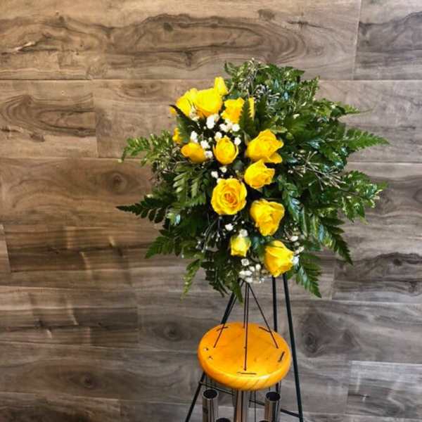 Yellow rose arrangement on a tall stand with greenery and white filler flowers