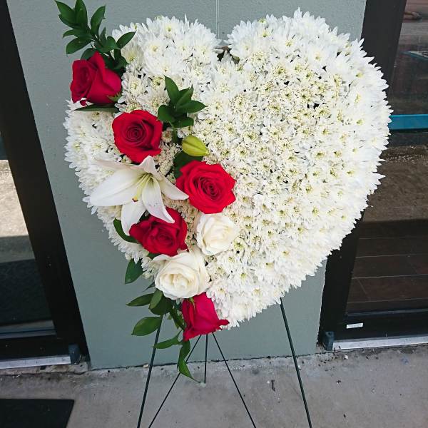 Heart-shaped floral spray with white blooms and red roses on a stand