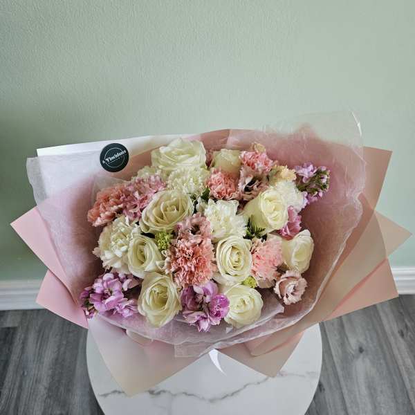Bouquet of cream roses and pink carnations wrapped in pastel paper