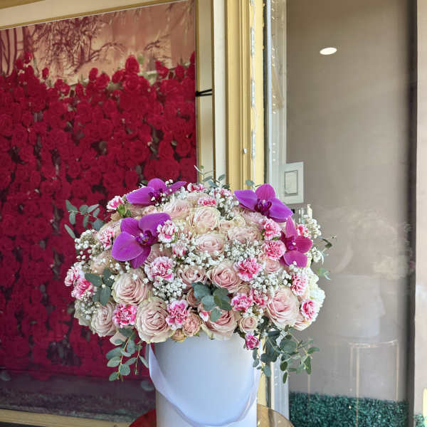Large pink rose arrangement in a white hatbox with purple orchids