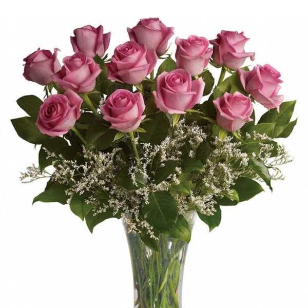 Pink roses arranged in a clear glass vase with white filler flowers
