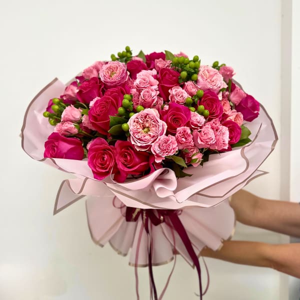 Bouquet of pink and magenta roses wrapped in pale pink paper