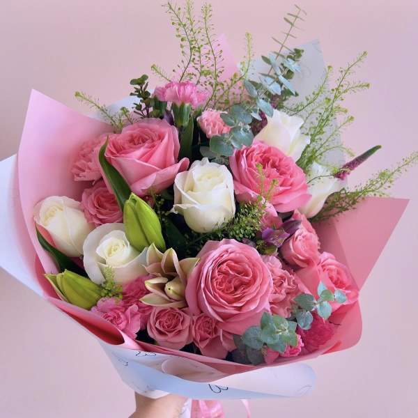 Pink and white rose bouquet with lilies and eucalyptus in pastel wrap
