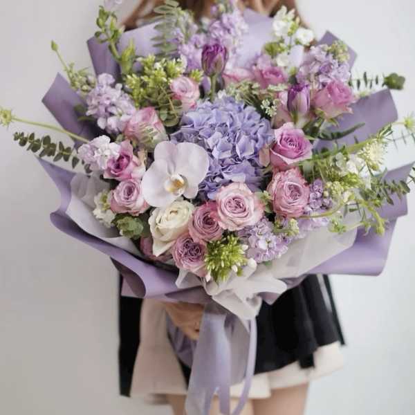 Large bouquet of pink and lavender flowers wrapped in purple paper