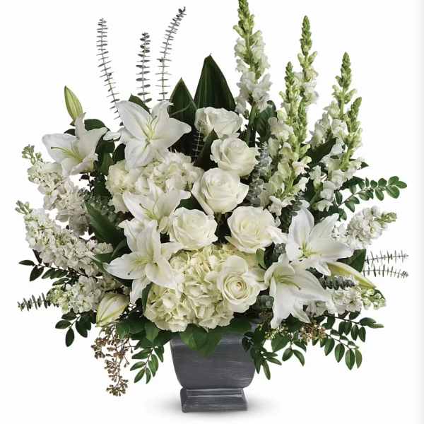 White lilies and roses arranged in a gray urn vase