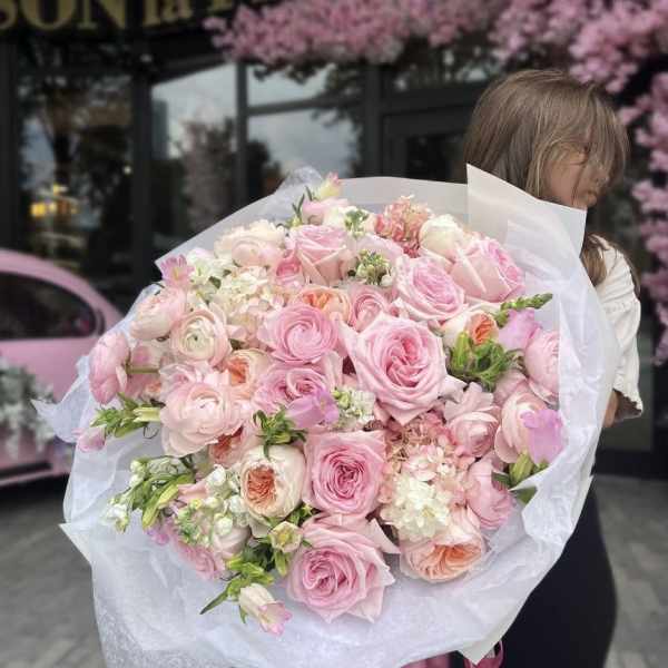 Large bouquet of pink roses and pale mixed blooms wrapped in white paper