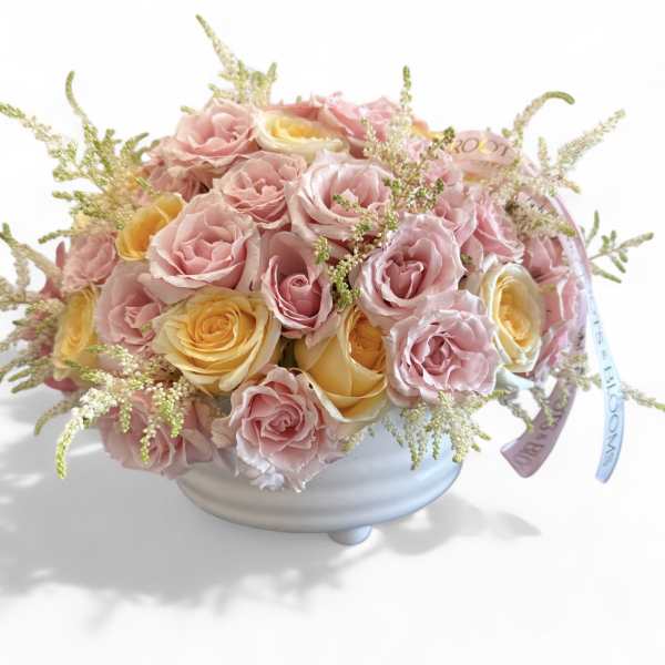 Pink and yellow roses arranged in a white bowl