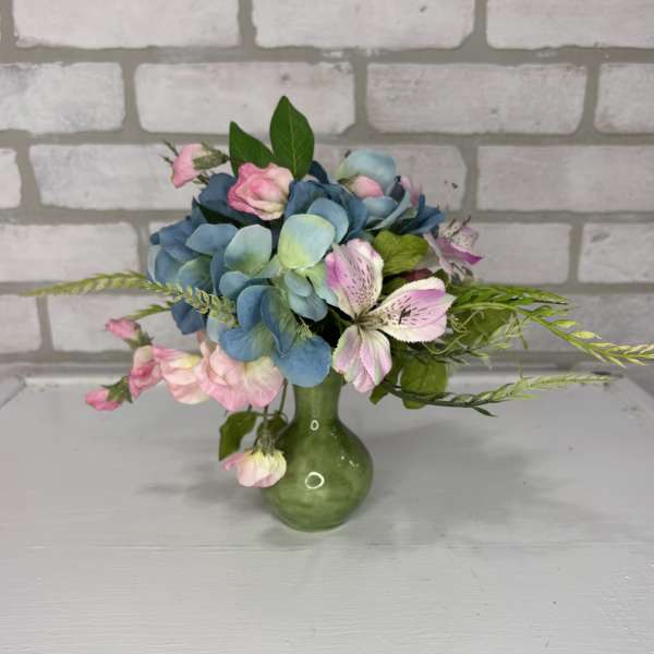 Blue hydrangeas and pink flowers in a green vase