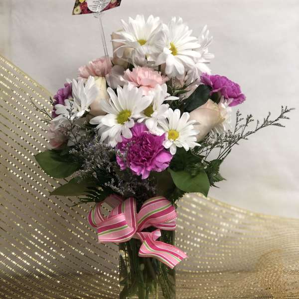 Bouquet of white daisies, pink carnations, and pale roses in a glass vase