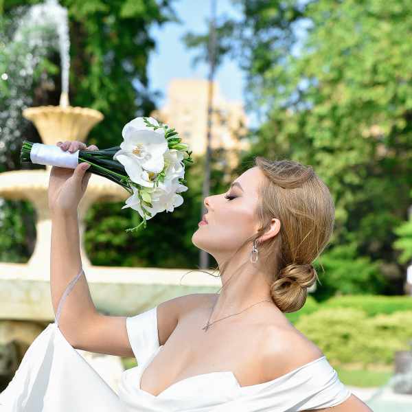 Bride holding a white orchid bouquet outdoors