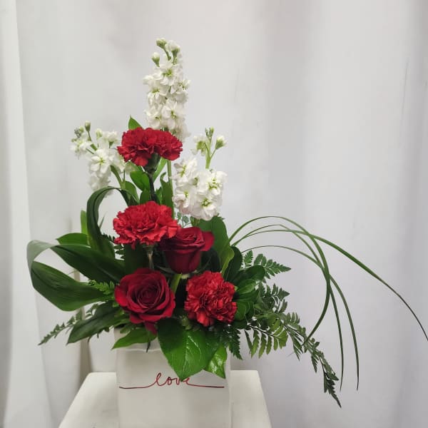 Red roses and carnations with white flowers in a white box