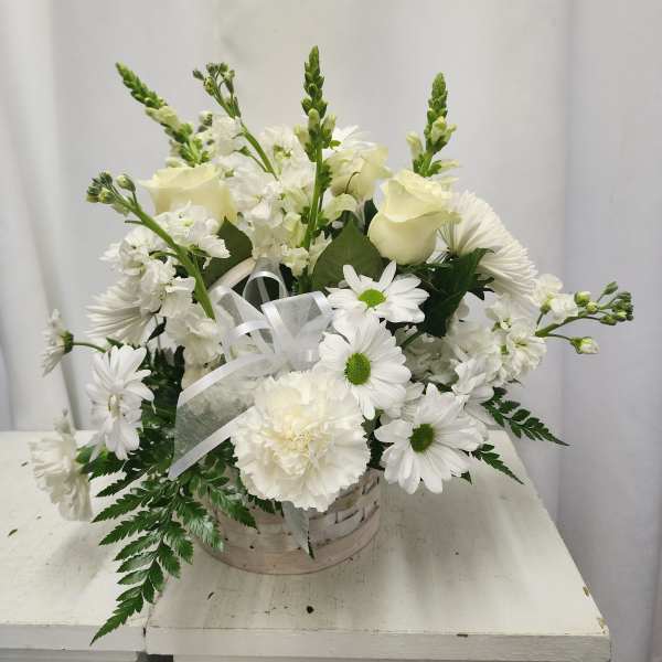 White floral arrangement in a basket with ribbon
