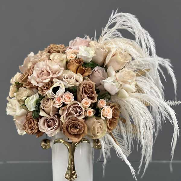 Bouquet of blush and beige roses in a white vase with white feathers
