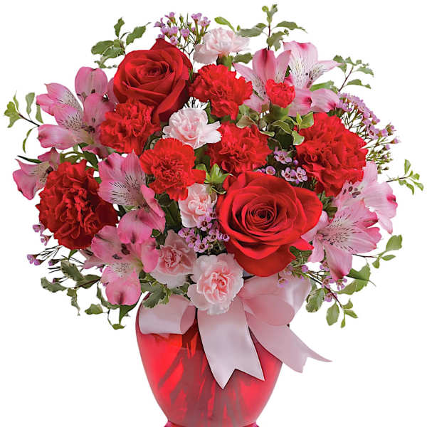 Red roses and pink flowers arranged in a red vase with a ribbon
