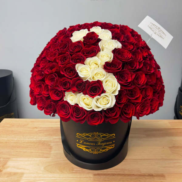 Large red and white rose arrangement in a black hatbox