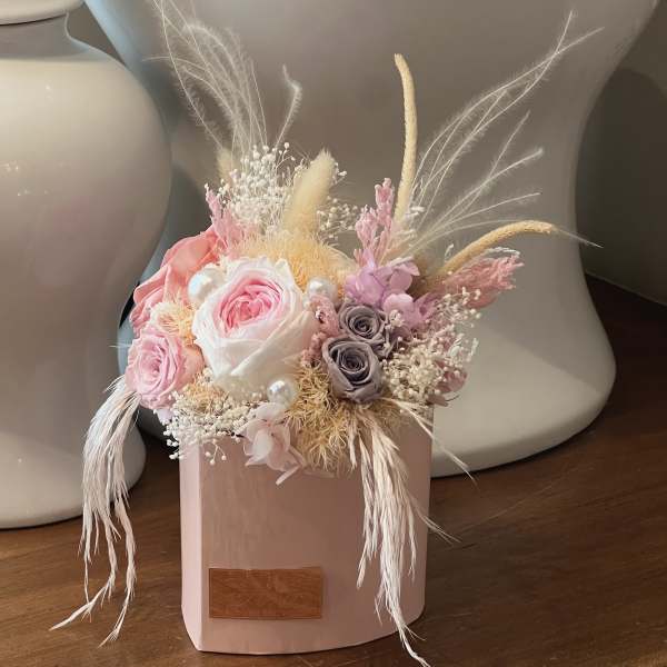 Pink and white rose arrangement in a blush box with dried feathers