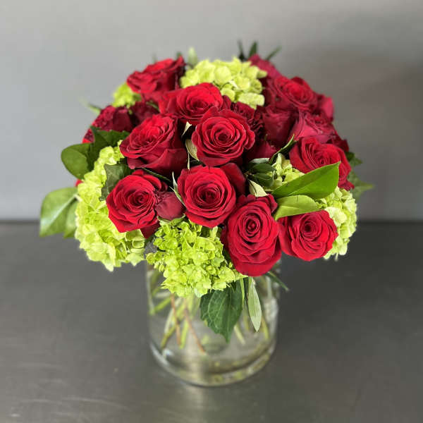 Red roses and lime-green hydrangeas in a clear glass vase
