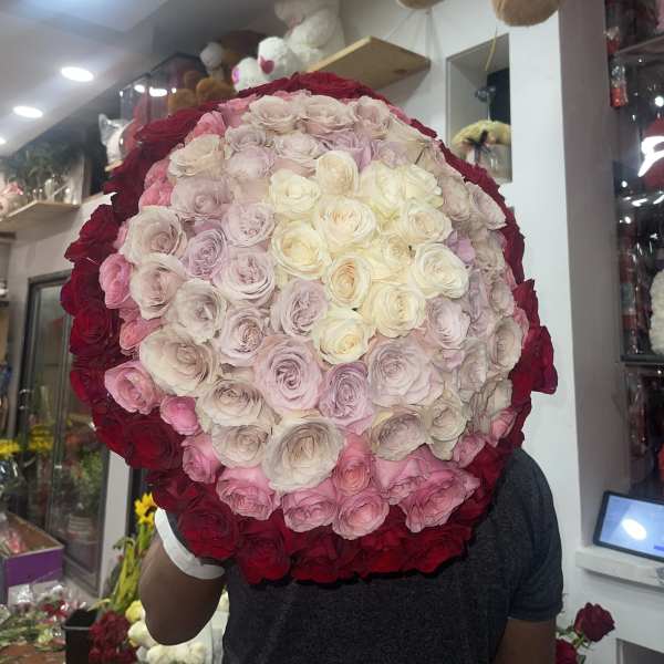 Large round bouquet of pink, cream, and red roses