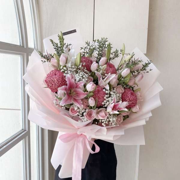 Pink bouquet with lilies, roses, and chrysanthemums wrapped in pale paper