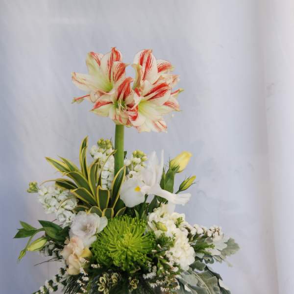 Tall floral arrangement with red-striped white lilies in a metal vase