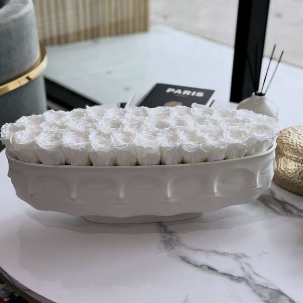 White roses arranged in a low oval ceramic vase