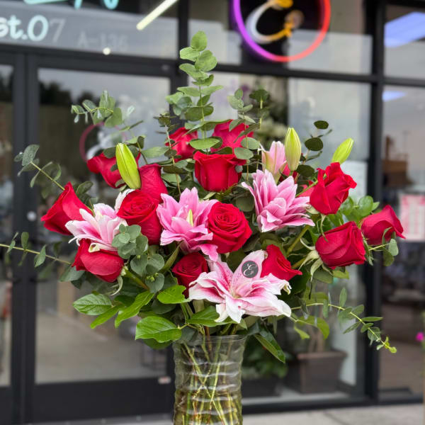 Red roses and pink lilies in a clear glass vase