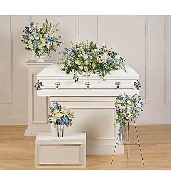White casket with blue and white floral sprays in a funeral setting