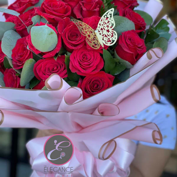 Bouquet of red roses wrapped in pink paper with a butterfly decoration