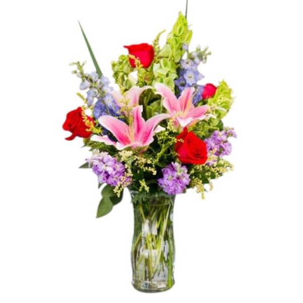 Mixed bouquet of pink lilies and red roses in a glass vase