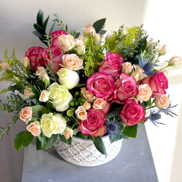 Pink and cream roses arranged in a white patterned bowl