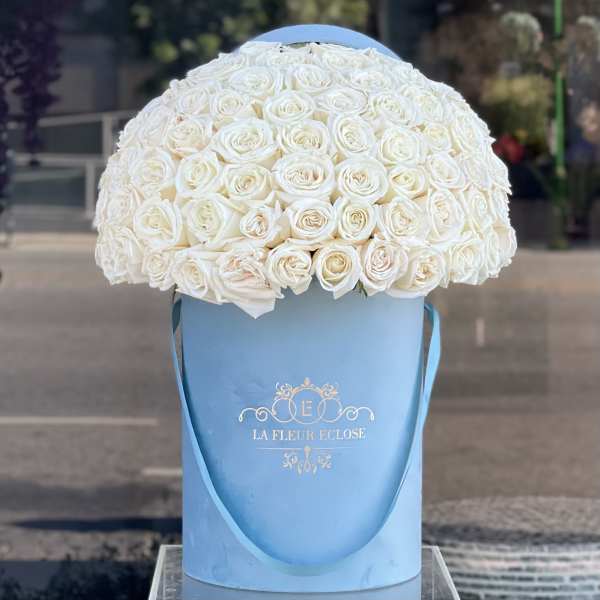 White rose bouquet in a blue hatbox with ribbon handles